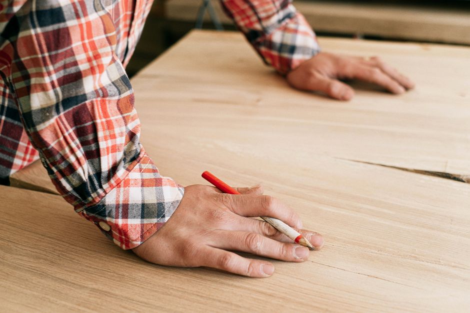 A craftsman marking wood in a workshop, focusing on precision i detalje.